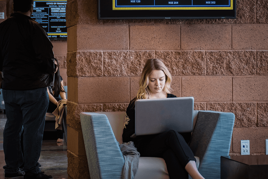 student sitting and typing on her laptop