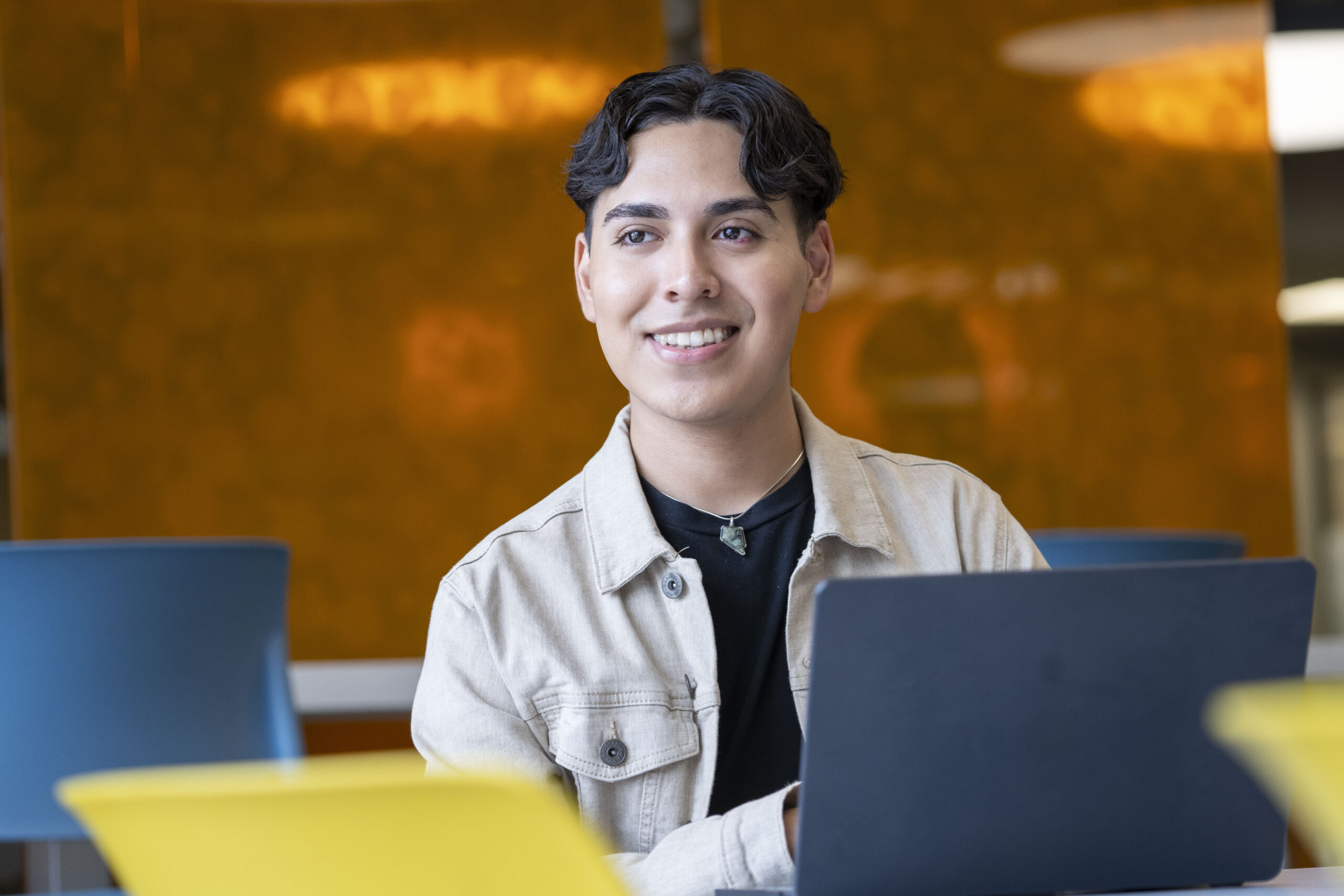 Student working on laptop looks up to smile