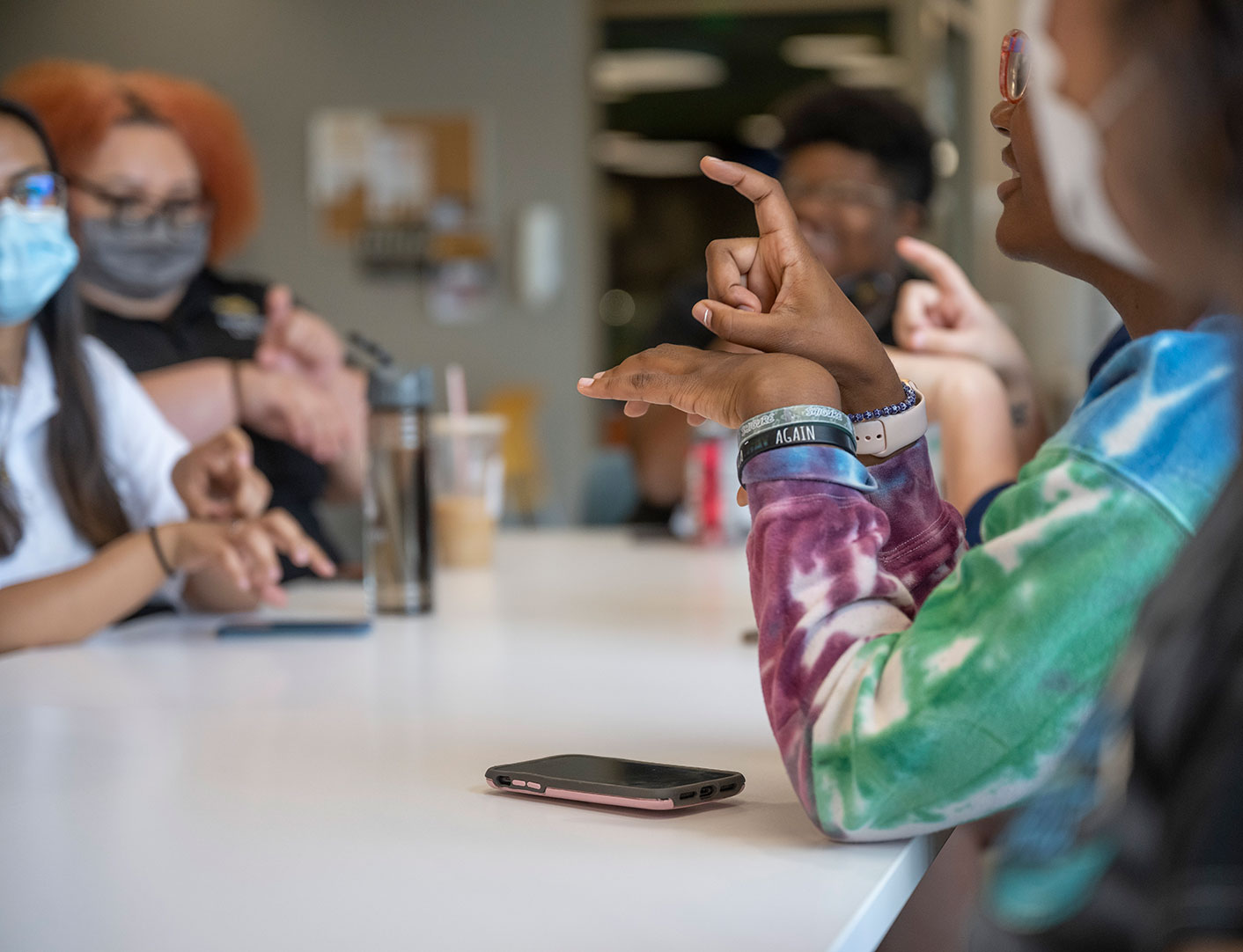 People sitting around a table talking and learning sign language