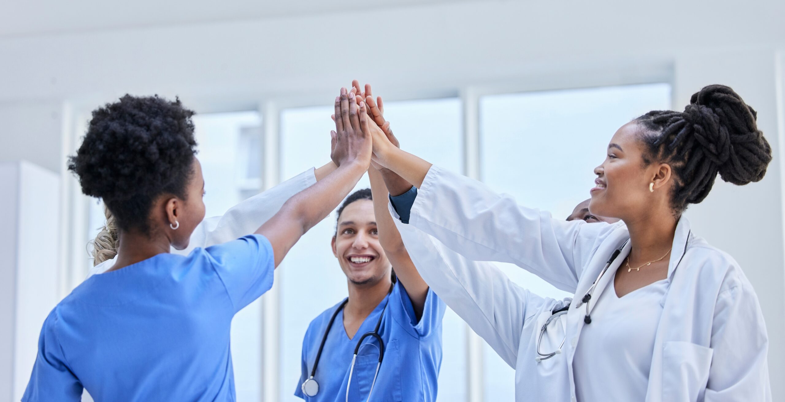 A group of healthcare professionals high fiving each other in a show of teamwork and celebration.