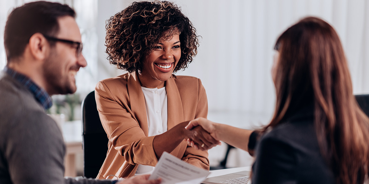 woman meeting with two professionals and shaking a hand
