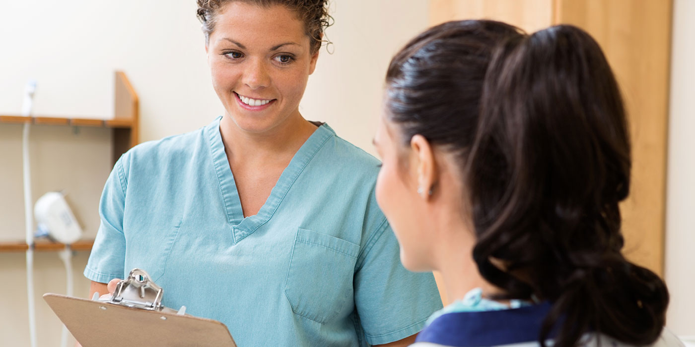 ccma-ges180 Nurse with a clipboard speaking to a woman