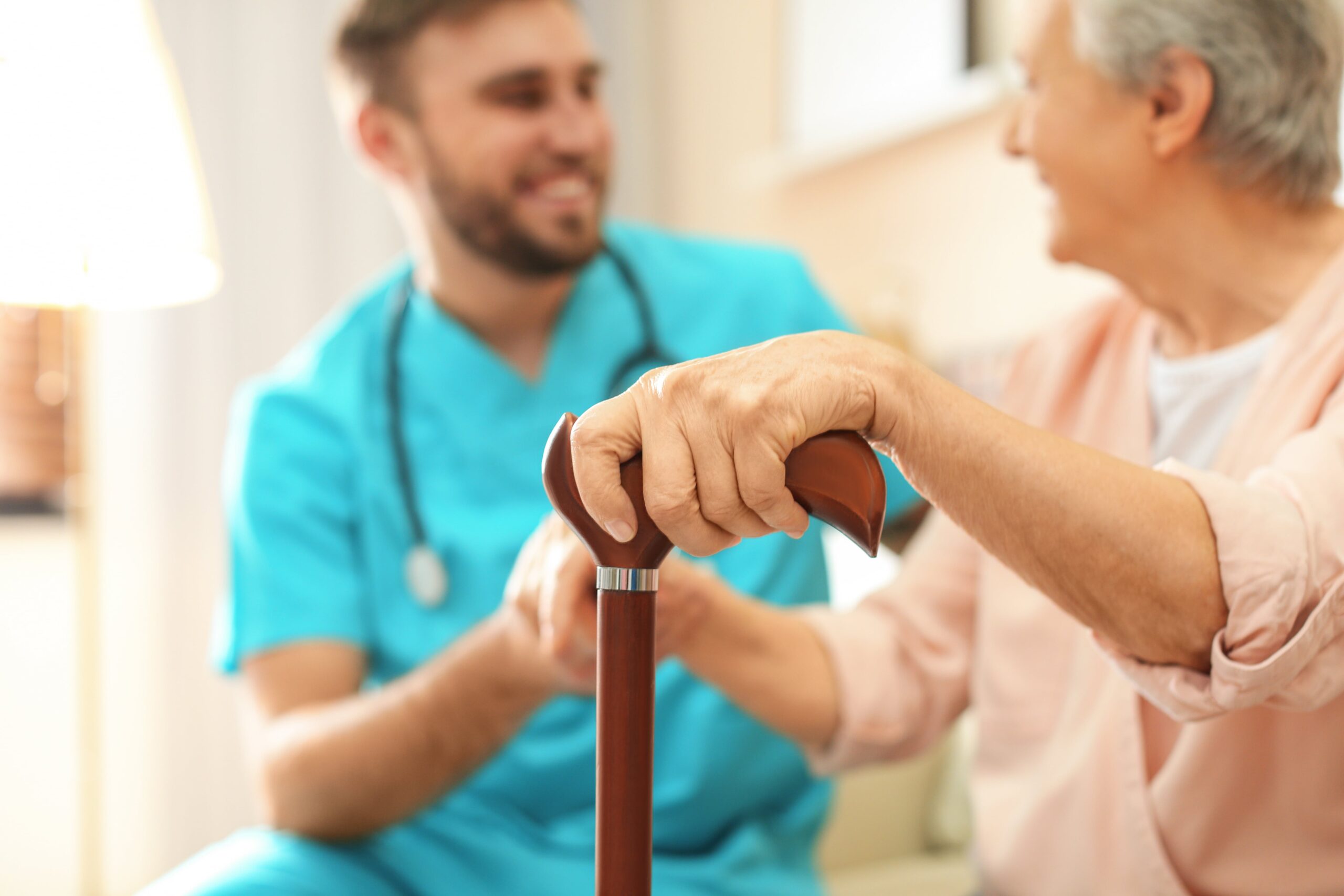 Nurse interacting with elderly woman holding a cane, showing supportive geriatric care.