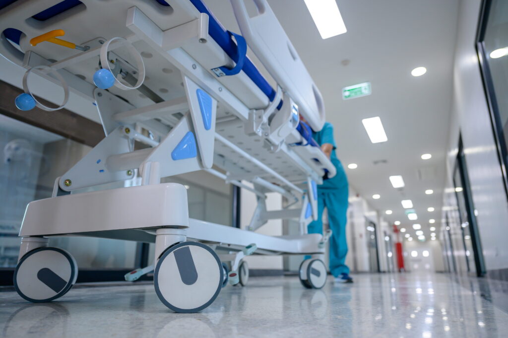 Hospital stretcher being pushed down a hallway by medical staff.