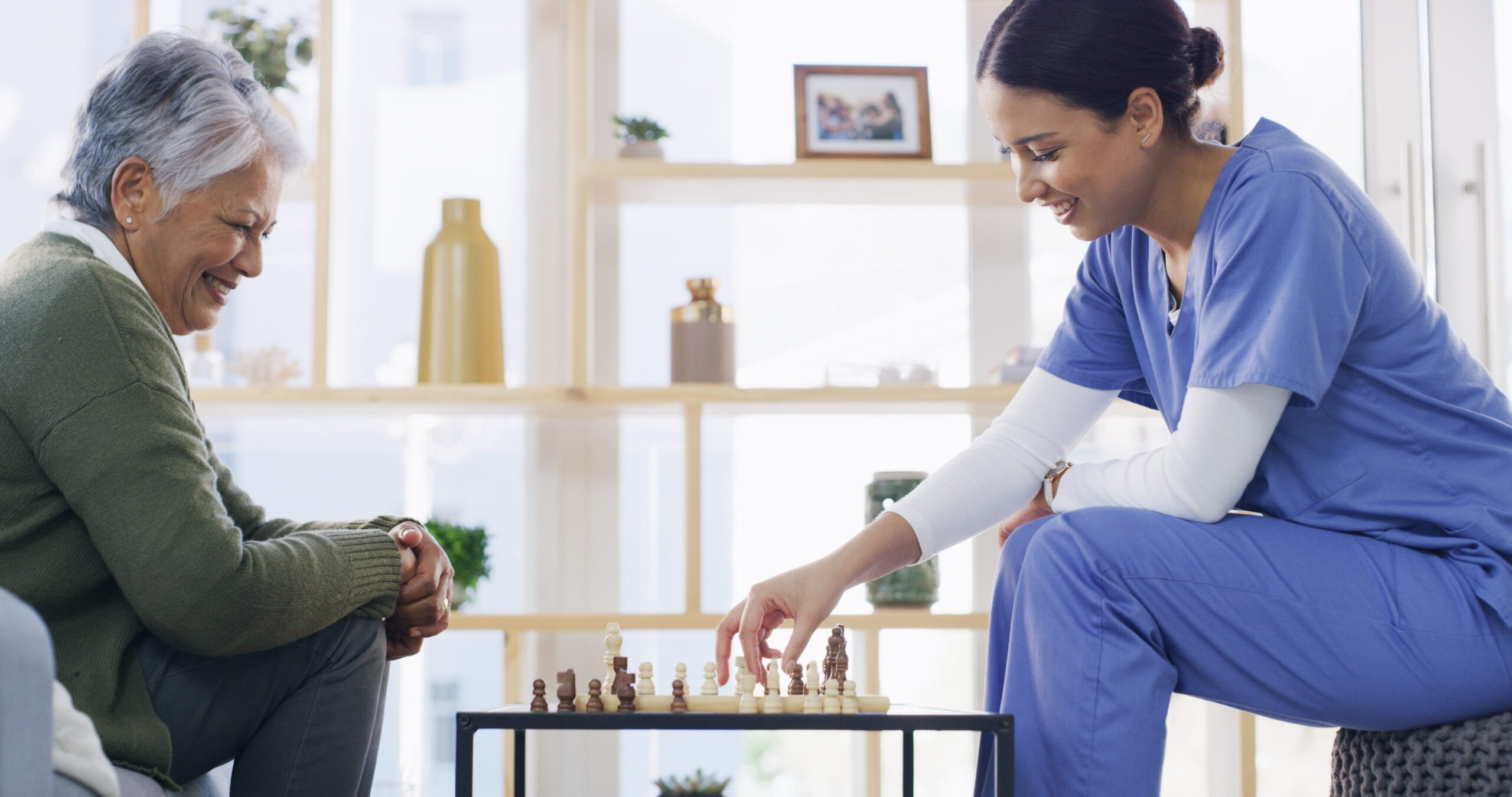 ltc_nurse-min2 Long-term care nurse playing chess with an older patient to support social engagement and emotional well-being.
