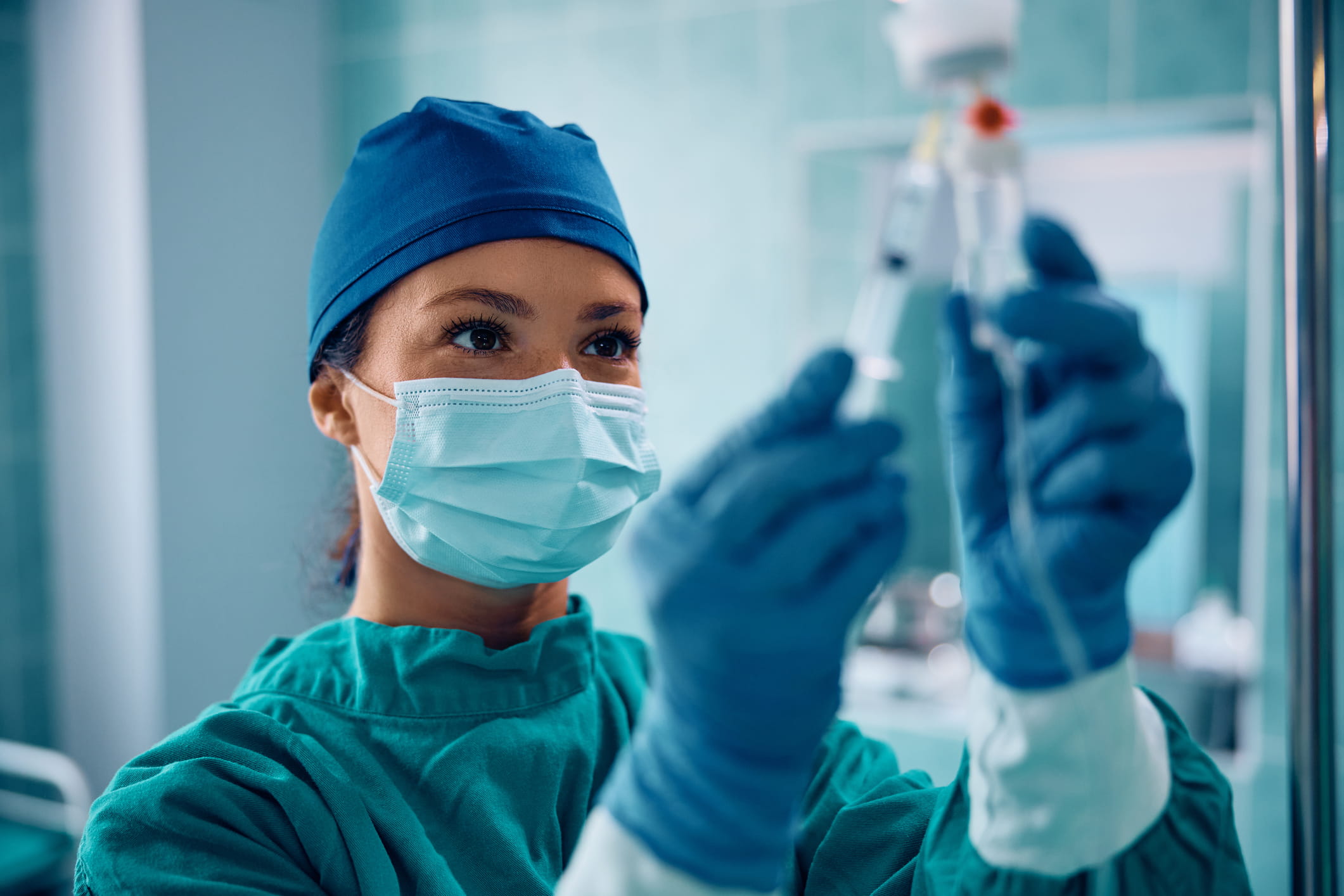 nurse-anesthetist-min1 Nurse anesthetist preparing medication and checking an IV line before a procedure.