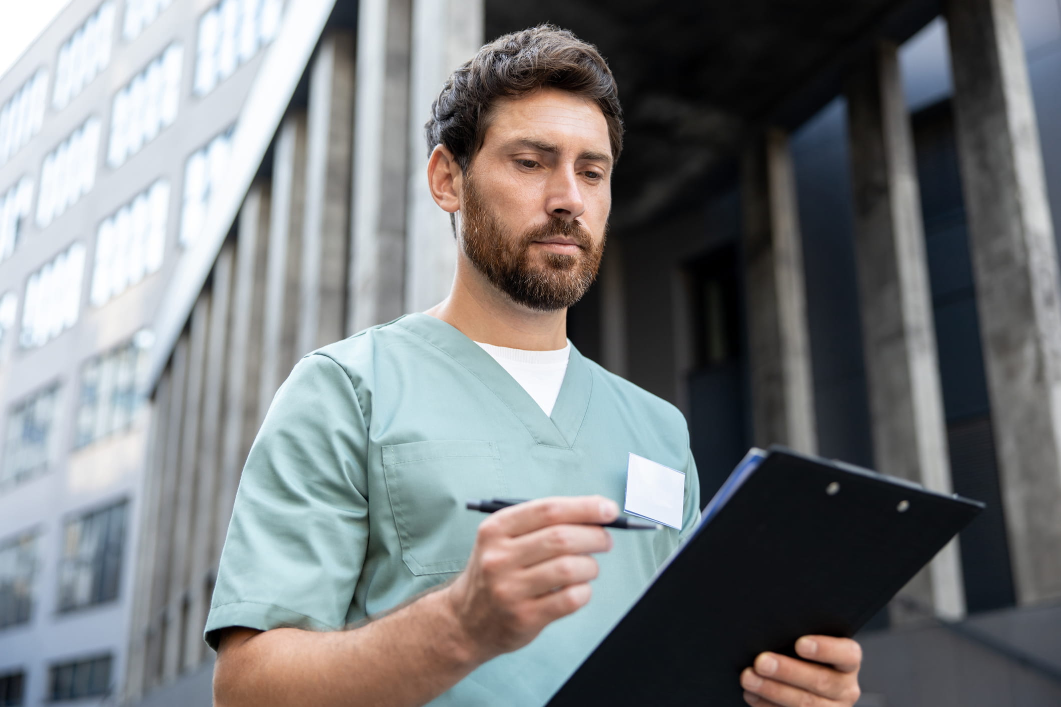 nurse-protection-min2 Nurse reviewing information on a clipboard outside a healthcare building.