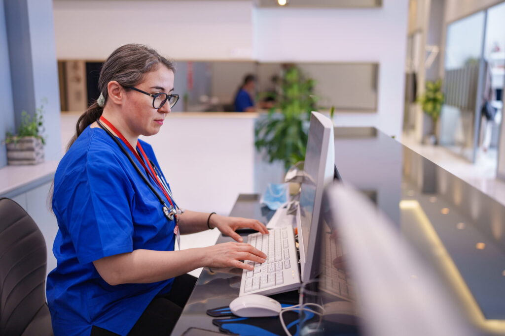 Public health nurse working at a computer to document patient and community health information.