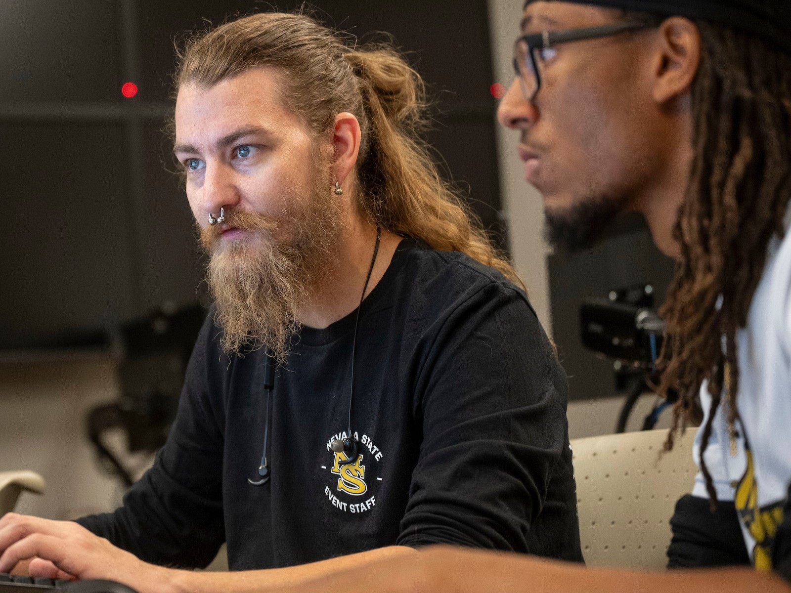 <br />
This photograph captures two individuals working together at a computer in what appears to be a collaborative or technical workspace.